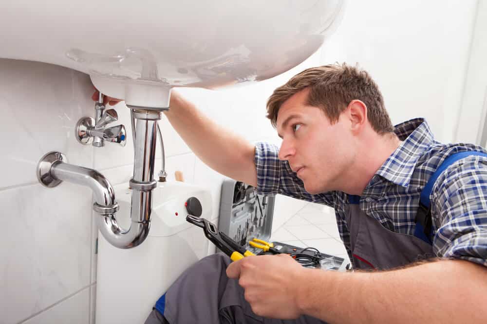 plumber checking leaks under sink